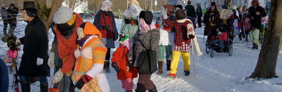 A group of mummers in colorful disguises walking down a snowy Newfoundland street