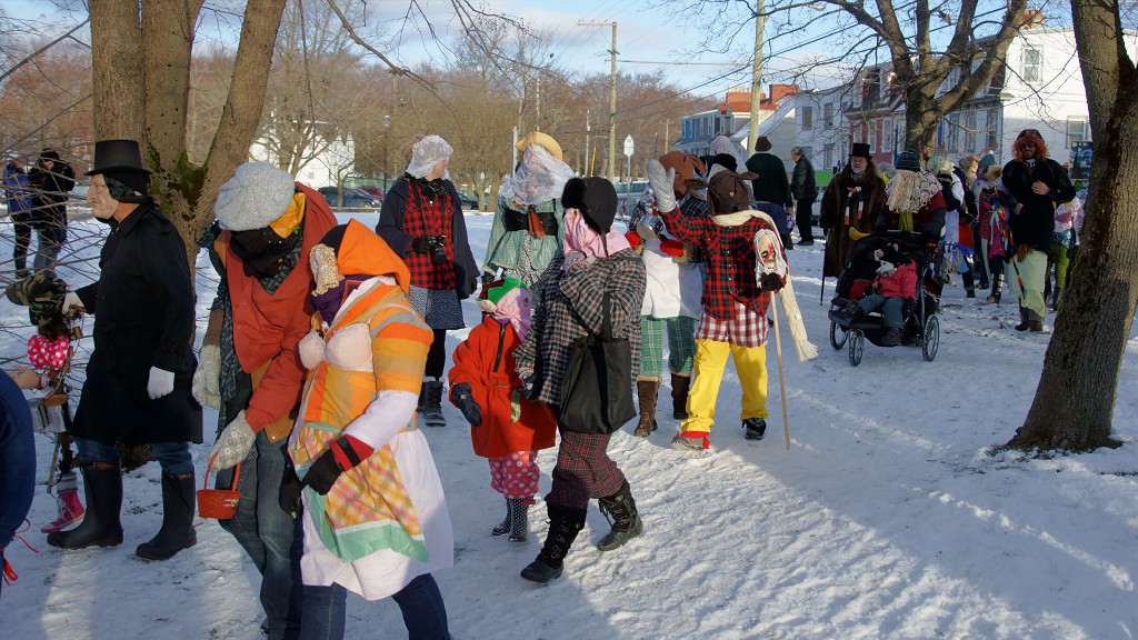 A group of mummers in colorful disguises walking down a snowy Newfoundland street. 