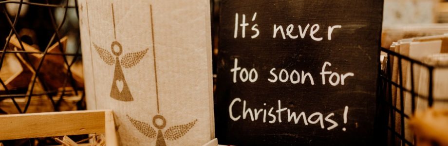 "It's never too soon for Christmas!" written on a slate board on a retail Christmas table.